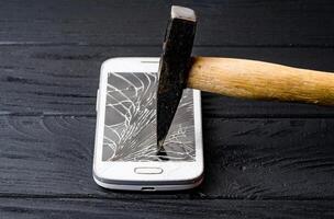 Smartphone with broken screen on dark background. Close-up photo