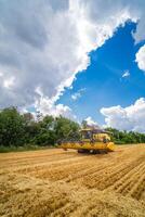 Yellow combine harvester working at field. Agricultural machine on blue sky. photo