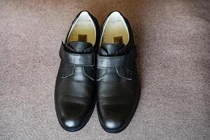 A pair of smart children's shoes standing together. Black leather boys school shoes isolated on a plain background. Close-up photo