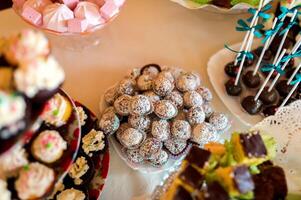 Delicious cookies on the wedding table for guests on the white tablecloth. Cake pops and lollipops, colorful cupcakes, confectionery buffet. Close-up photo