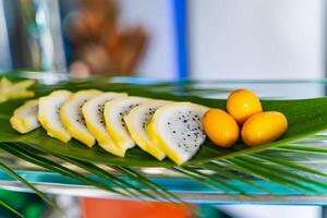 Fresh exotic fruits nicely decorated for guests on a big green leaf. Tropical assortment of organic fruits. Close-up photo