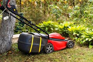 Lawnmower on green grass in sunny day outdoor. Special manual machine for grass cutting. Gardening concept. photo