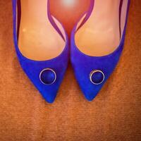 Blue wedding shoes with golden rings on the brown background. Preparation for wedding concept. Close-up photo