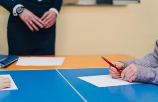 Hand of student is taking exam and writing answer in classroom for education test concept photo