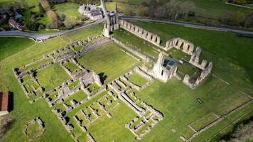 Aerial view of ancient abbey ruins in lush green landscape. photo