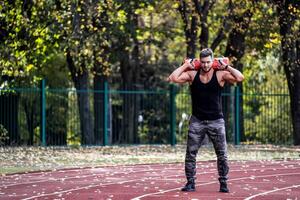 Handsome man exercising outdoors. Muscular sportsman training in green wide park. photo