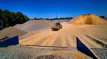 Sand quarry, excavating equipment, bulldozer with heap of sand and gravel in background. Selective focus. photo