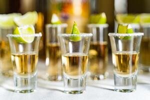 lentes de alcohol y Lima en el restaurante mesa. selectivo atención y Copiar espacio, tequila tiros, vodka, whisky, Ron con limón. foto
