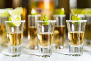 Glasses of alcohol and lime on the restaurant table. Selective focus and copy space, tequila shots, vodka,whisky, rum with lemon. photo