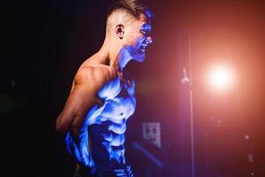 Brutal strong athletic men pumping up muscles. Workout and bodybuilding concept. Blue light filter. Handsome man with naked torso. Fitness model is posing. photo