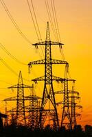 Energy Distribution Network - Electricity Pylons against Orange and Yellow Sunset. Selective focus. photo