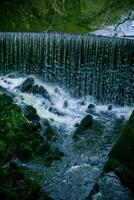 Serene waterfall cascading over a rocky ledge into a tranquil pool surrounded by lush greenery. photo