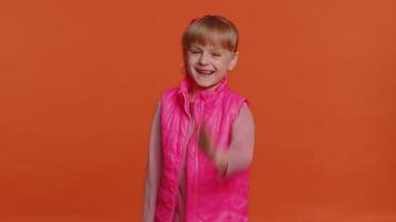 Toddler girl smiling friendly at camera and waving hands gesturing hello or goodbye, welcoming video