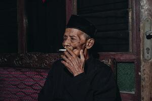 Portrait of an elderly Asian man smoking a cigarette. photo