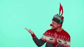 hombre en rojo suéter Papa Noel Navidad demostración pulgares arriba y señalando vacío lugar, publicidad zona video