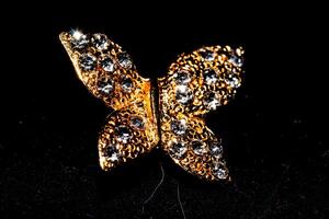 Elegant golden butterfly brooch with sparkling gemstones on a black background. photo