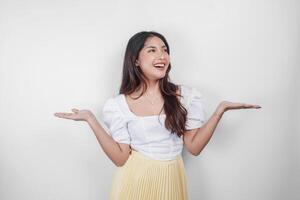 A cheerful Asian woman is pointing copy space beside her, isolated by white background. photo