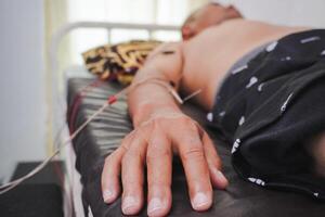 Closeup needles on patient body stimulated by electric. Acupuncture, Chinese alternative medicine. photo