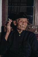 Portrait of an elderly Asian man smoking a cigarette. photo