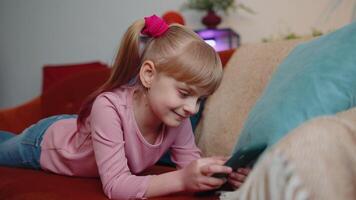 Child toddler hold smartphone watching funny cartoons, chatting with friends on couch alone at home video