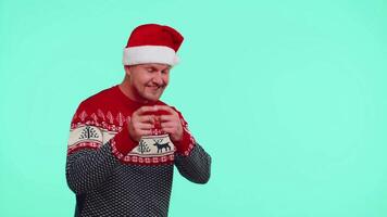 Man wears red New Year sweater deer showing thumbs up and pointing at on blank advertisement space video