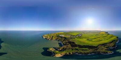 Panoramic aerial view of a lush green island surrounded by blue ocean under a clear sky in Flamborough, England photo
