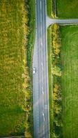 Aerial view of a car driving on a rural road with green fields on either side in Yorkshire. photo