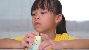 ásia pequeno fofa menina segurando rubik's cubo dentro dela mãos e jogando com isto. rubik's cubo é uma jogos este aumenta inteligência para crianças. video