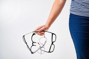 a woman holds four models of eyeglasses with different frames in her hand on a white background in the studio. Close-up photo