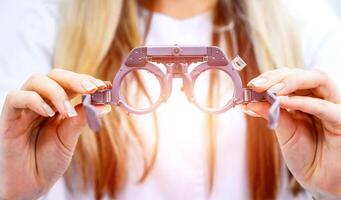 Close up of a phoropter in woman's hands, ophthalmologist in a blurred background. tool for ophthalmologists. Vision correction photo