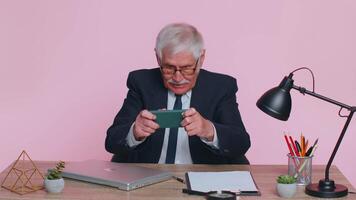 Worried senior businessman sits at workplace avoid working and playing racing or shooter video games