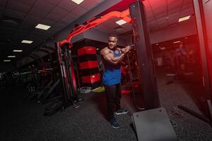 Healthy handsome man working in the gym. Strong bodybuilder with powerful muscles posing for camera. photo