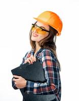 Happy young woman is wearing orange safety helmet, yellow glasses and checkered shirt holding a clipboard note. Isoalted background. photo