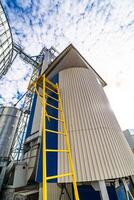 Big yellow stair near hangar warehouse on blue sky. Great cylindric warehouse on blue and white sky. photo