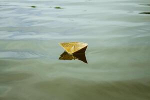 A white paper ship floating on water photo