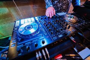 dj plays trendy music on a mixer console in the nightclub photo