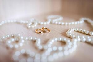 A pair of gold wedding rings in the white pearl background. Closeup. photo
