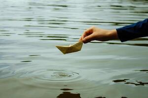 The boy launches a boat on a water close-up photo