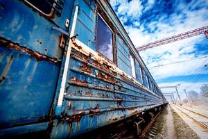 old rusty weathered peeled paint of an old wagon. Blue abandoned railway carriage. Old railwaystation. photo