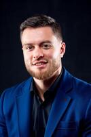 Attractive young guy posing in studio. Portrait of a handsome man with light beard and nice face. Confident look to the camera. Vertical photo