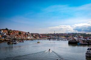 escénico ver de un costero pueblo con barcos y claro azul cielo en Whitby, Inglaterra. foto