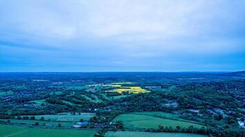 Aerial view of a lush countryside landscape at dusk with fields and trees under a moody blue sky. photo