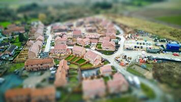 Aerial view of a quaint village with tilt-shift effect, creating a miniature scene with blurred surroundings. photo