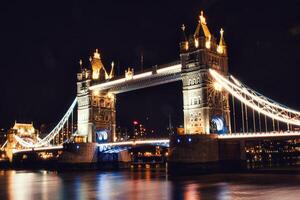 Night view of the illuminated Tower Bridge in London with reflections on the Thames River. photo