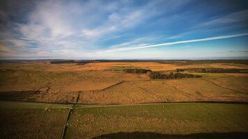 Panoramic view of a vast rural landscape with fields under a wide blue sky with clouds at Sycamore Gap, Northumberland, UK. photo