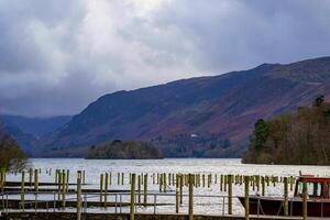 Misty lake with wooden jetty and mountains in the background on an overcast day. photo