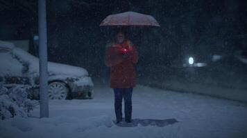 Young African Woman Standing on Street at Night During Snow Fall with Umbrella video