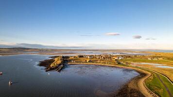 Aerial view of a coastal village with boats and a curving road at sunset. photo