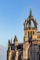 Historic gothic church spires against a clear blue sky with soft sunlight in Edinburgh, Scotland. photo