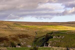 Rolling hills with lush greenery under a dramatic cloudy sky in Yorkshire Dales. photo